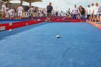 Participants throw egg-shaped metal balls on blue playing fields at the Boules Ovales tournament as a local version of the typical French boules game in front of Criee aux Poissons during the Fete de la Saint-Louis, Sete, Herault, Occitanie, France [IBR125405020]