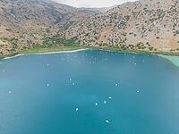Kournas Lake at the foot of the mountains during peak tourist season, with many visitors enjoying pedal boats in clear sunny weather on Crete island [IBR125405083]