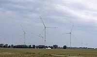 An extensive wind farm with numerous wind turbines characterizes the flat agricultural landscape in Schleswig-Holstein. Under a cloudy sky, the facilities stand between fields and rows of trees. Symbolic picture of wind energy, energy transition, climate  [IBR125405084]