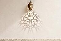 Traditional ornate hanging lantern casting a beautiful Islamic geometric shadow on a textured beige wall, AI generated [IBR125407387]