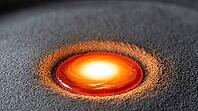 Close-up of a brilliant white-hot molten titanium weld pool with orange and red edges on a bed of fine grey titanium powder, active laser fusion moment, industrial macro photography, AI generated [IBR125407416]