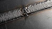 Close-up of two overlapping solidified metal weld tracks with fine ripple texture and a subtle remelted seam, full frame texture, industrial macro photography, additive manufacturing, AI generated [IBR125407449]