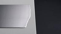 Smooth continuous metallic lithium deposition layer spreading laterally across a flat pale grey ceramic substrate, charcoal background, industrial lighting, high temperature battery science, AI generated [IBR125407477]
