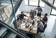Heated workplace conflict, agile team crisis, project failure, high stress levels and burnout among engineers during chaotic hardware development, furious developers arguing intensely around a wooden conference table covered in tangled wiring, open laptop [IBR125414121]