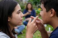 Interpersonal intimacy and tactile connection between young adults in a park, nonverbal communication during authentic emotional dialogue, direct eye contact and playful physical gesture between two friends symbolise immediate sensory presence, the finger [IBR125414129]
