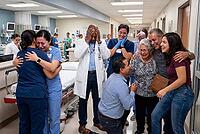 Hospital staff and family celebrating miraculous medical recovery in emergency ward, healthcare workers experiencing overwhelming emotional relief, weeping nurses hugging each other in clinical scrub uniforms, an exhausted physician holding head in disbel [IBR125414141]