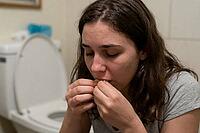 Young woman dealing with secret eating habits, bulimia nervosa, mental health struggles, gastrointestinal discomfort, emotional distress in private bathroom, a distressed female sitting near open toilet while consuming food discreetly, psychiatric vulnera [IBR125414152]