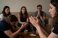 Group therapy, spiritual counseling, emotional support circle, youth prayer meeting, empathetic communication, collective vulnerability and compassion, young adults seated together addressing psychological distress and interpersonal healing, communal refl [IBR125414180]