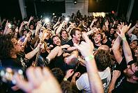 Ecstatic crowd surfing at energetic live music concert, passionate fans celebrate underground youth culture and collective euphoric togetherness, lifted audience member smiles amidst densely packed venue hall, electric bass headstock emerges from passiona [IBR125414181]