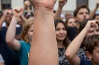 Civic activism and collective empowerment at a street demonstration, raised fists signify grassroots democracy, political participation, social reform, a dominant foreground forearm reaching upward embodies individual agency within collective mobilization [IBR125414212]