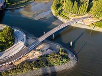 Aerial view of the curved Entenwerder Bridge across the Oberhafen Canal with a waterfront path on the Norderelbe near Rothenburgsort, Hamburg, Germany [IBR113394945]