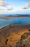 View of steep cliffs to sea and the island of La Graciosa, Mirador del Porrito viewpoint at sunset, Lanzarote, Canary Islands, Spain [IBR125414243]