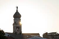 Sunrise behind the bell tower of the Assumption Cathedral with baroque onion dome and trumpet blowing angel, old town of Krk, island of Krk, Croatia [IBR125415385]