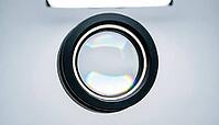 Close-up of a circular optical lens element with iridescent anti-reflective coating mounted in a matte black housing, spectrometer optics photography, clinical studio lighting, AI generated [IBR125421214]