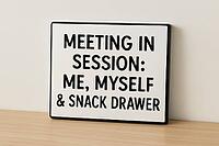 Funny sign with the writing meeting in session, me, myself and snack drawer standing on a wooden desk against a white wall, AI generated [IBR125421217]
