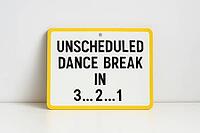 White sign with yellow border announcing an unscheduled dance break in 3, 2, 1, placed on a white surface against a white wall background, AI generated [IBR125421225]