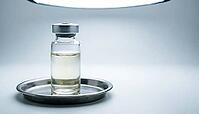 Clear glass sensor calibration reference vial with colorless liquid on a stainless steel tray, clinical laboratory studio lighting, analytical instrumentation photography, AI generated [IBR125421233]
