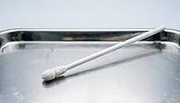 Close-up of a single unused white fiber trace sample collection swab on a stainless steel tray, clinical studio lighting, forensic sample collection photography, AI generated [IBR125421247]