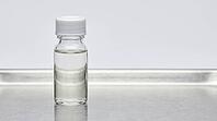 Clear glass sensor calibration reference vial with colorless liquid on a stainless steel tray, clinical laboratory studio lighting, analytical instrumentation photography, AI generated [IBR125421256]