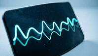 Abstract glowing cyan and teal vital signs waveform display with no readable numbers, dark curved surface, cardiac monitoring concept, clinical macro photography, AI generated [IBR125421283]
