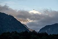 Glaciated impressive mountain peak, mountains with forest, last clouds of fog moving around in the morning, Carretera Austral, near Villa Santa Lucia, Los Lagos, Chile [IBR125423492]