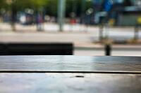 Empty wooden table surface in foreground with a blurry urban street scene backdrop [IBR125424538]