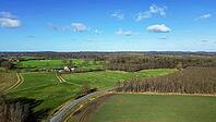 Aerial view showing German countryside with agricultural land, forests, and farm building [IBR125436241]