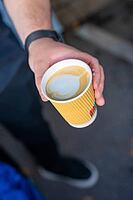 A hand presents a mug of latte art on a street, Sindelfingen, Germany [IBR125436244]