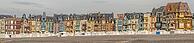 The Belle epoque and Art Nouveau in the seaside resort of Mers-les-Bains. Beach cabins sit on pebbles by the shore. Colorful buildings rise. Mers-les-Bains, Somme, France [IBR125436305]