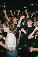 Youthful euphoria and collective effervescence among dancing teenagers in an energetic nightlife setting, emotional liberation and vibrant celebration, raised fists and victorious gestures manifest uninhibited joy, dynamic clubbing atmosphere intertwines  [IBR125446420]