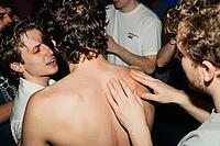 Tactile connection, nocturnal hedonism, youth subculture and authentic emotional intimacy unite during crowded club party celebrations, bare skin contact beneath harsh flash illumination embodies vulnerability, kinetic energy within crowded underground ga [IBR125446428]