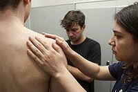 Manual physical therapy examination and shoulder palpation in modern clinical rehabilitation, diagnostic assessment of musculoskeletal tension, a professional therapist gently evaluates the deltoid and scapular region of a bare young male patient, tactile [IBR125446431]