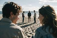 Interpersonal connection among young adults on sandy coastal terrain under harsh daylight reveals diverse group dynamics and thoughtful reflections, two blurry figures in the foreground frame three distant companions standing in deep conversation near bre [IBR125446437]