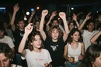 Ecstatic youth crowd dancing with raised hands at live music concert inside vibrant nightclub, celebrating freedom, community and nightlife culture, young people immersed in rhythmic euphoria, fists raised into the air create a powerful symbol of unity, c [IBR125446438]