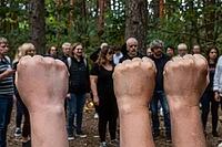 Clenched fists raised in solidarity for grassroots environmental activism and civil resistance, diverse group of people gather in woodland glade, collective empowerment and social cohesion in natural forestry landscape, symbolic gesture of unity against c [IBR125446445]