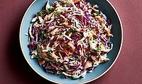 Fresh coleslaw salad with shredded purple cabbage, carrots, and herbs. Served on blue plate against deep red background, AI generated [IBR125446453]