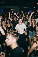 Euphoric young crowd dancing together in a vibrant nightclub atmosphere, celebrating youth culture, electronic dance music and social connection, raised arms and synchronized movements manifest the psychological release of dopamine and collective efferves [IBR125446460]