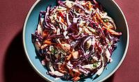 A bowl of vibrant coleslaw with red cabbage, carrots, and creamy dressing, served in a blue dish, AI generated [IBR125446472]