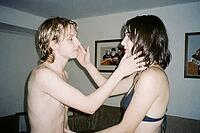 Young intimate couple sharing tender affectionate touch indoors with wet hair after swimming, shirtless man and woman embracing each other face to face in domestic apartment living room, close emotional bonding between romantic partners, raw youth vulnera [IBR125446480]