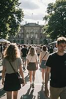 Vibrant crowd of young college students walking towards an imposing historic university palace building, sunny daylight casting natural rim lighting, collective forward movement representing generational aspirations and higher education pathways, diverse  [IBR125446487]