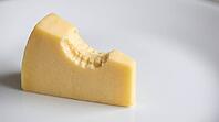 Close-up of a clean bite mark with visible tooth impressions in a pale yellow cheese wedge, matte white surface, forensic odontology demonstration substrate photography, AI generated [IBR125446497]