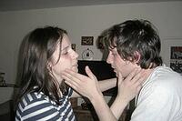 Intimate domestic communication between young partners experiencing emotional tension, tactile touch on faces represents interpersonal vulnerability, nonverbal conflict resolution and psychological connection within a private living space, subtle ambivale [IBR125446504]