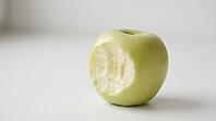 Close-up of a clean bite mark with visible tooth impressions in a pale green apple, matte white surface, forensic odontology demonstration substrate photography, AI generated [IBR125446505]