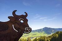 A rusty metal cow marks Alpe Schwanden as a traditional alpine farm, the flat silhouette also serves as a signpost and regional symbol in the mountain area on Mittagberg, 1452m, above Immenstadt, Allg$00E4u, Bavaria, Germany [IBR125448859]