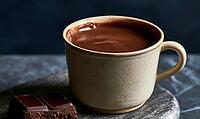 Warm cup of melted chocolate sits on stone surface. Dark chocolate bar rests nearby. Smooth, rich liquid shines under soft lighting, AI generated [IBR125448876]