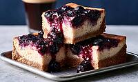 Three blueberry cheesecake slices stacked on a metal tray. Dark blueberries glisten on top of creamy cake. Warm lighting highlights texture, AI generated [IBR125448883]