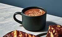 Dark ceramic mug holds rich hot chocolate with cinnamon swirl. Light gray textured table surface. Partially visible baked goods nearby, AI generated [IBR125448884]
