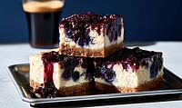 Two stacked blueberry cheesecake slices on metal plate. Dark background with coffee cup behind. Slightly blurred background, AI generated [IBR125448887]