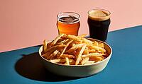 Bowl of golden french fries sits on blue surface. Two glasses of beer stand behind. One glass contains amber beer, other dark beer, AI generated [IBR125448895]