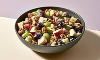 Fresh fruit salad in dark bowl. Mixed apple, grape, celery, and walnut pieces. Vibrant colors contrast with soft background, AI generated [IBR125448898]